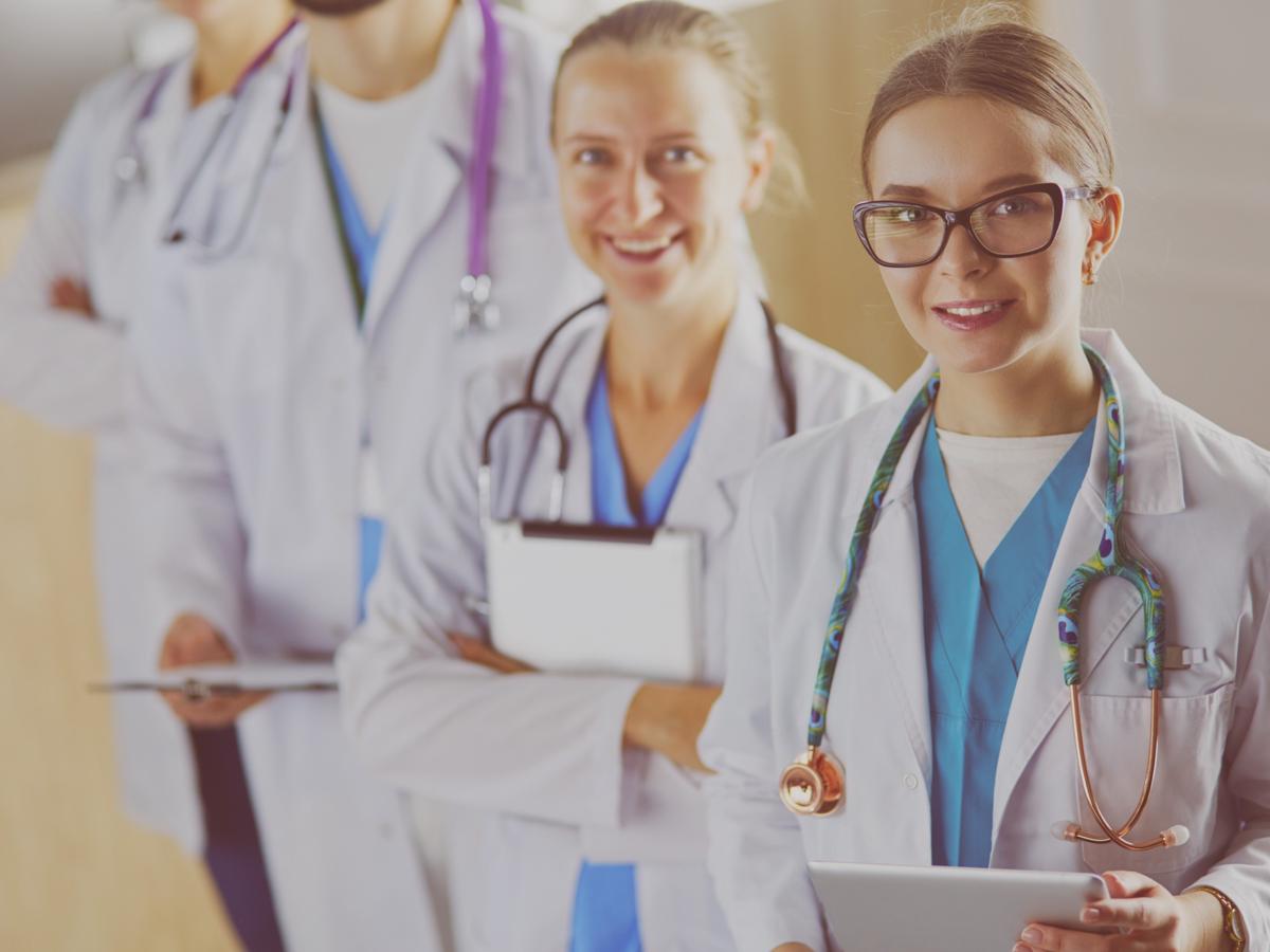 A group of healthcare professionals stands confidently in a modern clinic, ready to provide excellent patient care. Their smiles reflect dedication and teamwork, showcasing the importance of collaboration in the medical field.
